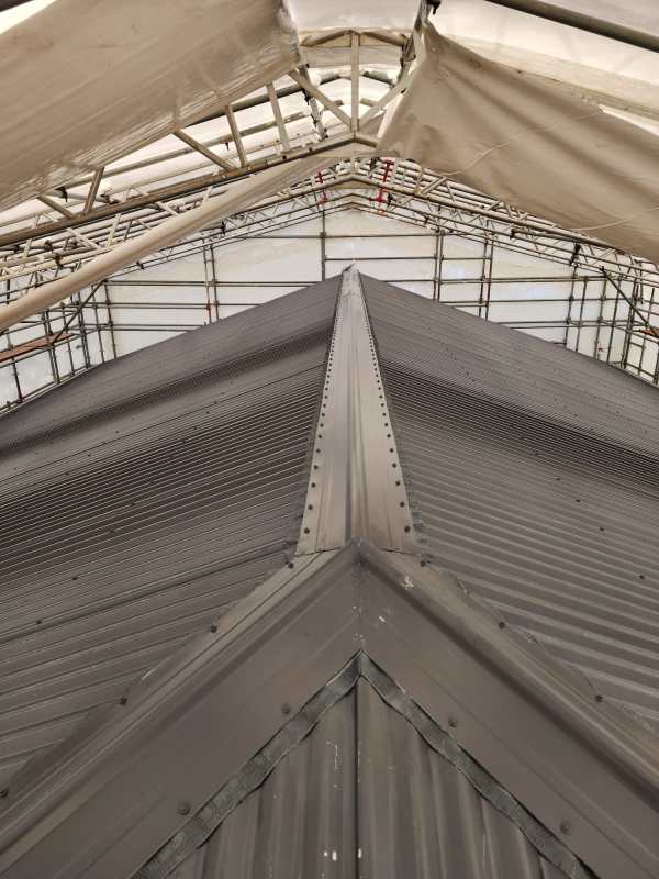 Industrial corrugated metal roof under a protective scaffolding structure