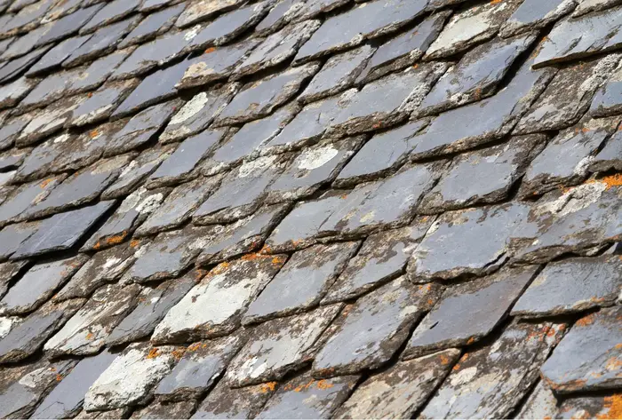 Close-up of an aging slate roof with visible cracks and weathering.