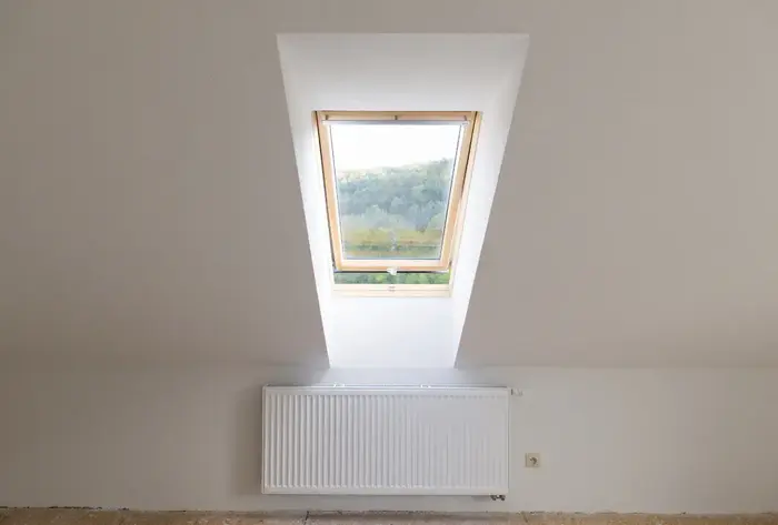 Attic space with a skylight window above a radiator