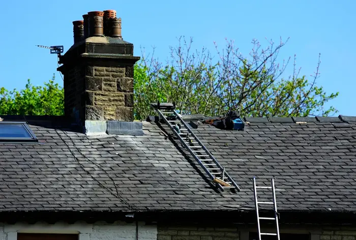 House with a stone chimney and slate roof showing wear