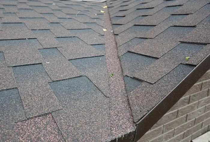 Close-up of a roof valley with overlapping asphalt shingles and slight debris buildup.