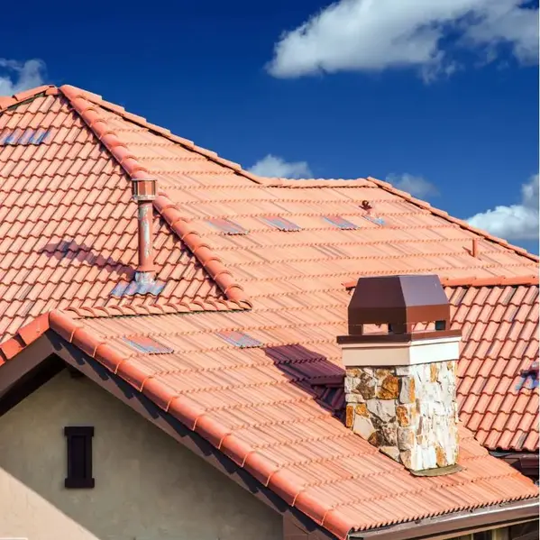 House with a red terracotta tile roof and a stone chimney