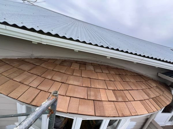 Newly installed wooden shingles under a metal roof