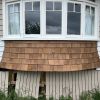 House exterior with freshly installed wooden shingles under a bay window