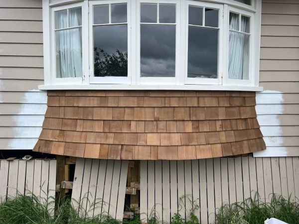 House exterior with freshly installed wooden shingles under a bay window